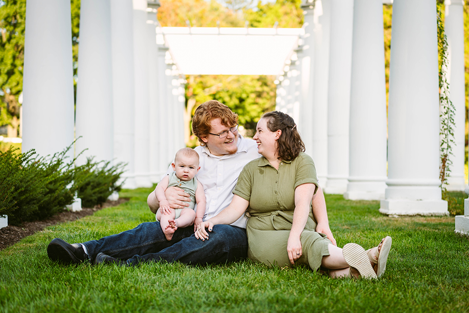 A family of three, including a baby, posing together during a professional family portrait session at Lakeside Park.