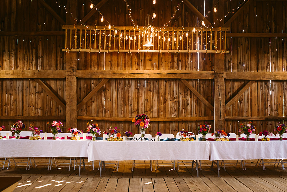 Rustic barn interior adorned with string lights, creating a warm and charming atmosphere for the wedding reception.