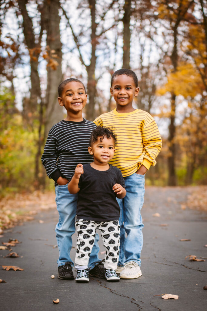 Three siblings laughing together at sunset in Fort Wayne, captured during a natural, candid family photo session